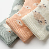 Close-up of girls baby socks in pastel tones with playful embroidered designs